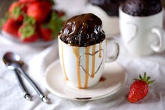 Le gâteau de chocolat délicieux a fait cuire dans une micro-onde dans une tasse avec le sirop de caramel Image libre de droits Le gâteau de chocolat délicieux a fait cuire dans une micro-onde dans une tasse avec le sirop de caramel Image libre de droits