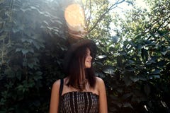 Le hippie élégant heureux de femme se tenant au vert laisse le mur en soleil image libre de droits Le hippie élégant heureux de femme se tenant au vert laisse le mur en soleil image libre de droits