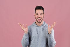 Le jeune homme attirant sourit ouverture large sa bouche dans la surprise et dans l'admiration étend ses mains devant lui photo stock Le jeune homme attirant sourit ouverture large sa bouche dans la surprise et dans l'admiration étend ses mains devant lui photo stock