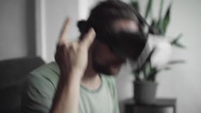Le jeune homme barbu de hippie employant son affichage de casque de VR pour observer les 360 visuels et se sent pendant qu'il est Le jeune homme barbu de hippie employant son affichage de casque de VR pour observer les 360 visuels et se sent pendant qu'il est