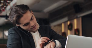 Le jeune homme d'affaires travaillant dans le bureau moderne ou Co-travaillant, parle par le téléphone et à l'aide de la montre i clips vidéos Le jeune homme d'affaires travaillant dans le bureau moderne ou Co-travaillant, parle par le téléphone et à l'aide de la montre i clips vidéos