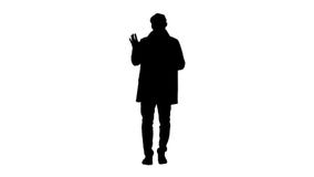 Le jeune homme de silhouette dans le manteau de foss? fait salut le geste photo libre de droits Le jeune homme de silhouette dans le manteau de foss? fait salut le geste photo libre de droits