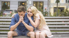 Le jeune homme a dérangé au sujet des problèmes, amie de support l'étreignant avec amour image stock Le jeune homme a dérangé au sujet des problèmes, amie de support l'étreignant avec amour image stock