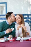 Le jeune homme embrasse son amie sur la joue, buvant du café dans un café image libre de droits Le jeune homme embrasse son amie sur la joue, buvant du café dans un café image libre de droits