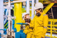 Le jeune homme et un petit gar?on sont tous deux dans un uniforme jaune, les verres, et le casque de travail dans un milieu indus photo libre de droits Le jeune homme et un petit gar?on sont tous deux dans un uniforme jaune, les verres, et le casque de travail dans un milieu indus photo libre de droits