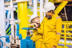 Le jeune homme et un petit gar?on sont tous deux dans un uniforme jaune, les verres, et le casque de travail dans un milieu indus photos stock Le jeune homme et un petit gar?on sont tous deux dans un uniforme jaune, les verres, et le casque de travail dans un milieu indus photos stock