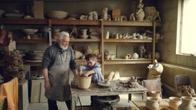 Le jeune petit-fils moule le clayware dans son studio du ` s de grands-pères tandis que son grand-papa supérieur affectueux est p banque de vidéos Le jeune petit-fils moule le clayware dans son studio du ` s de grands-pères tandis que son grand-papa supérieur affectueux est p banque de vidéos