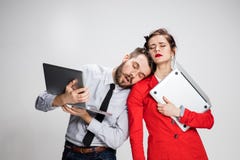 Le jeunes homme d'affaires et femme d'affaires avec des ordinateurs portables sur le fond gris image libre de droits Le jeunes homme d'affaires et femme d'affaires avec des ordinateurs portables sur le fond gris image libre de droits