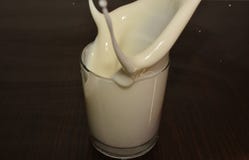 Le lait déborde une tasse sur la table photos stock Le lait déborde une tasse sur la table photos stock