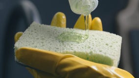 Le liquide transparent de vaisselle circule sur l'éponge pour les plats de lavage photo libre de droits Le liquide transparent de vaisselle circule sur l'éponge pour les plats de lavage photo libre de droits