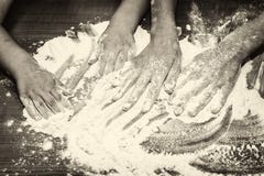 Le mani del bambino che mescolano farina sulla tavola fotografia stock Le mani del bambino che mescolano farina sulla tavola fotografia stock
