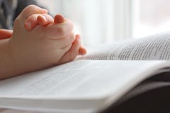 Le mani del bambino piccolo che pregano sulla bibbia santa fotografie stock Le mani del bambino piccolo che pregano sulla bibbia santa fotografie stock