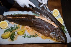Le mani del cameriere in guanti bianchi che tagliano pesce nel ristorante immagini stock libere da diritti Le mani del cameriere in guanti bianchi che tagliano pesce nel ristorante immagini stock libere da diritti