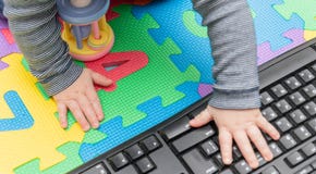 Le mani del piccolo bambino, su un topo del computer e su una tastiera - sviluppo infantile, ottenente esperto con tecnologia dal fotografia stock Le mani del piccolo bambino, su un topo del computer e su una tastiera - sviluppo infantile, ottenente esperto con tecnologia dal fotografia stock