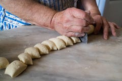 Le mani della donna anziana che tagliano pasta con la taglierina tradizionale della pasta fotografia stock libera da diritti Le mani della donna anziana che tagliano pasta con la taglierina tradizionale della pasta fotografia stock libera da diritti
