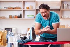Le mari de jeune homme faisant l'habillement repassant ? la maison images stock Le mari de jeune homme faisant l'habillement repassant ? la maison images stock
