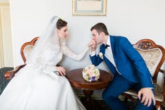 Le marié embrasse la main de la jeune mariée dans un bel intérieur photos stock Le marié embrasse la main de la jeune mariée dans un bel intérieur photos stock