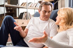 Le milieu a vieilli des couples parlant et se trouvant sur le lit à la maison photo stock Le milieu a vieilli des couples parlant et se trouvant sur le lit à la maison photo stock