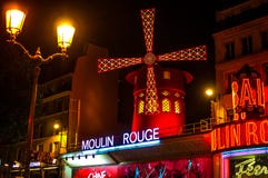 Le Moulin rouge est le cabaret de renommée mondiale à Paris chez Montmartre Une lumière très efficace de nuit et des lames tourna images stock Le Moulin rouge est le cabaret de renommée mondiale à Paris chez Montmartre Une lumière très efficace de nuit et des lames tourna images stock
