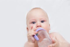 Le nourrisson boit d'une bouteille et d'un mensonge image stock Le nourrisson boit d'une bouteille et d'un mensonge image stock