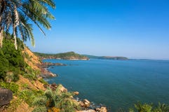 Le paysage est belle côte rocheuse avec le palmier, la mer bleue et le ciel sans nuages en plage de l'OM, Karnataka, Inde images stock Le paysage est belle côte rocheuse avec le palmier, la mer bleue et le ciel sans nuages en plage de l'OM, Karnataka, Inde images stock