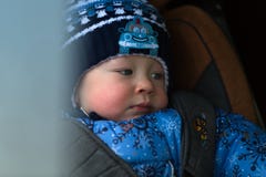 Le petit garçon en hiver vêtx d'un siège de voiture d'enfant Photo libre de droits Le petit garçon en hiver vêtx d'un siège de voiture d'enfant Photo libre de droits