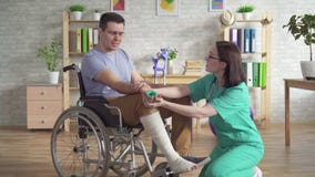 Le physiothérapeute aide une personne dans un fauteuil roulant après une blessure à faire des exercices avec l'extenseur de poign banque de vidéos Le physiothérapeute aide une personne dans un fauteuil roulant après une blessure à faire des exercices avec l'extenseur de poign banque de vidéos