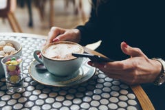 Le plan rapproché du ` s de femme remet tenir le téléphone portable tout en se reposant en café moderne Photos stock Le plan rapproché du ` s de femme remet tenir le téléphone portable tout en se reposant en café moderne Photos stock