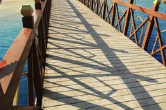 Le pont au-dessus de la rivière dans un ciel bleu de rail en bois concret de plancher de parc se reflète en bas de la rivière image libre de droits Le pont au-dessus de la rivière dans un ciel bleu de rail en bois concret de plancher de parc se reflète en bas de la rivière image libre de droits