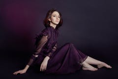 Le portrait arménien de femme de mode de contraste avec de grands yeux bleus se reposent sur un fond foncé dans une robe pourpre photographie stock Le portrait arménien de femme de mode de contraste avec de grands yeux bleus se reposent sur un fond foncé dans une robe pourpre photographie stock