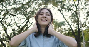 Le portrait de la jeune femme asiatique attirante sourit heureusement dans la caméra en parc d'été au coucher du soleil banque de vidéos Le portrait de la jeune femme asiatique attirante sourit heureusement dans la caméra en parc d'été au coucher du soleil banque de vidéos