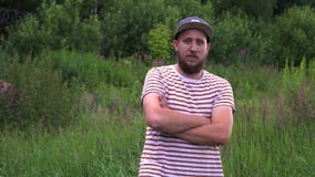 Le portrait du jeune homme drôle barbu avec le chapeau tournent autour et croisent des mains banque de vidéos Le portrait du jeune homme drôle barbu avec le chapeau tournent autour et croisent des mains banque de vidéos
