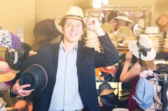 Le portrait du jeune type de sourire essayent le chapeau de seau au magasin photographie stock libre de droits Le portrait du jeune type de sourire essayent le chapeau de seau au magasin photographie stock libre de droits