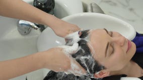 Le procedure femminili, ragazza castana con capelli lunghi visita un salone di bellezza per il lavaggio dei capelli con lo sciamp Le procedure femminili, ragazza castana con capelli lunghi visita un salone di bellezza per il lavaggio dei capelli con lo sciamp