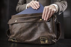 Le professeur dans une veste obtient un livre d'une vieille serviette en cuir Photos stock Le professeur dans une veste obtient un livre d'une vieille serviette en cuir Photos stock