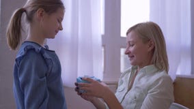 Le présent à la mère, peu de fille donne le cadeau d'anniversaire et les étreintes de sourire de maman tendrement et se réjouit à Le présent à la mère, peu de fille donne le cadeau d'anniversaire et les étreintes de sourire de maman tendrement et se réjouit à
