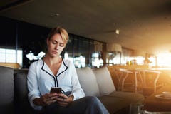 Le Président fier de jeune femme utilise le téléphone portable, tandis qu'attend des associés dans le restaurant pendant son voya photographie stock Le Président fier de jeune femme utilise le téléphone portable, tandis qu'attend des associés dans le restaurant pendant son voya photographie stock