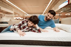 Le père barbu beau avec le jeune fils examine le matelas pour la douceur photos libres de droits Le père barbu beau avec le jeune fils examine le matelas pour la douceur photos libres de droits