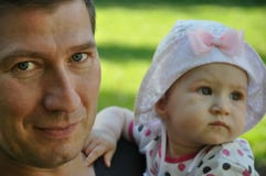Le père de sourire avec ses de bébé de fille portraits dehors sur le vert a brouillé le fond images stock Le père de sourire avec ses de bébé de fille portraits dehors sur le vert a brouillé le fond images stock