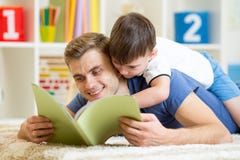 Le père et le fils ont lu un livre sur le plancher à la maison images stock Le père et le fils ont lu un livre sur le plancher à la maison images stock