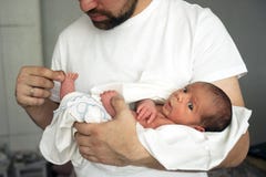 Le père tient le fils nouveau-né nu dans des ses mains dans une couche-culotte blanche photos stock Le père tient le fils nouveau-né nu dans des ses mains dans une couche-culotte blanche photos stock