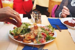Le ragazze mangiano l'insalata di Caesar nel ristorante fotografia stock Le ragazze mangiano l'insalata di Caesar nel ristorante fotografia stock