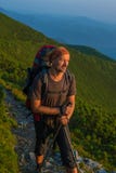 Le randonneur avec le sac à dos repose et regarde le Soleil Levant dans le MOIS Photos libres de droits Le randonneur avec le sac à dos repose et regarde le Soleil Levant dans le MOIS Photos libres de droits