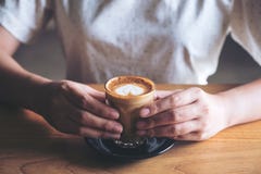 Le ` s de femme remet tenir un verre de café chaud avec l'art de latte de coeur sur la table en bois de vintage Photos libres de droits Le ` s de femme remet tenir un verre de café chaud avec l'art de latte de coeur sur la table en bois de vintage Photos libres de droits