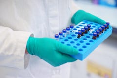 Le scientifique de laboratoire tient une boîte en plastique avec des échantillons de liquide transparent dans les fioles photographie stock Le scientifique de laboratoire tient une boîte en plastique avec des échantillons de liquide transparent dans les fioles photographie stock