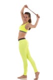 Le soutien-gorge et les guêtres jaunes au néon de port de sports de femme sexy de brune étirant le tronc latéral muscles avec une photographie stock Le soutien-gorge et les guêtres jaunes au néon de port de sports de femme sexy de brune étirant le tronc latéral muscles avec une photographie stock