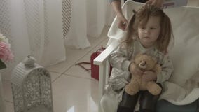 Le styliste en coiffure faisant des boucles utilisant un fer de cheveux à la petite jolie fille soit beau banque de vidéos Le styliste en coiffure faisant des boucles utilisant un fer de cheveux à la petite jolie fille soit beau banque de vidéos