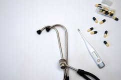 Le stéthoscope, le thermomètre électronique et les pilules jaunes se trouvent sur un fond blanc photographie stock libre de droits Le stéthoscope, le thermomètre électronique et les pilules jaunes se trouvent sur un fond blanc photographie stock libre de droits