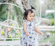 Le support de petite fille de plan rapproché sur le panier en acier de bicyclette pour décorent à l'arrière-plan de jardin avec l photo stock Le support de petite fille de plan rapproché sur le panier en acier de bicyclette pour décorent à l'arrière-plan de jardin avec l photo stock