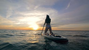 Le surfer féminin monte un paddleboard dans un océan ouvert le soir 4K clips vidéos Le surfer féminin monte un paddleboard dans un océan ouvert le soir 4K clips vidéos